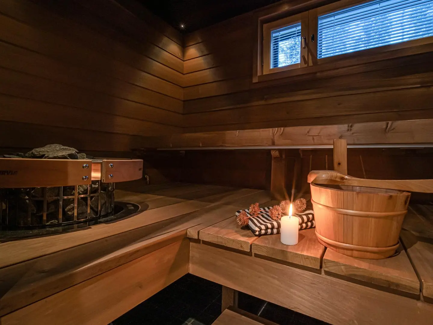 milis_sauna An athmospheric wooden sauna with a candle, a towel and wooden sauna bucket.