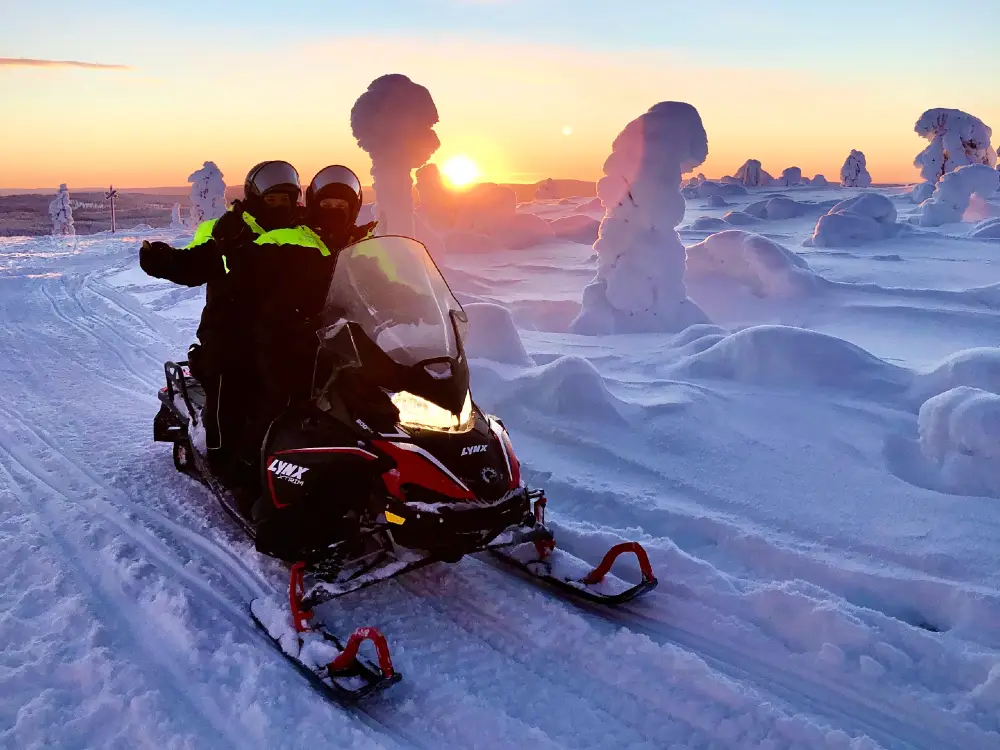 snowmobiling_1000_750 Huskyride in a snowy forest. Sun shining and a fell visible in the background.