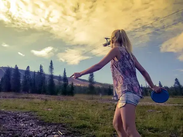 frisbeegolf_yllas5 A woman throwing a frisbee in a sunset, fell on the background.