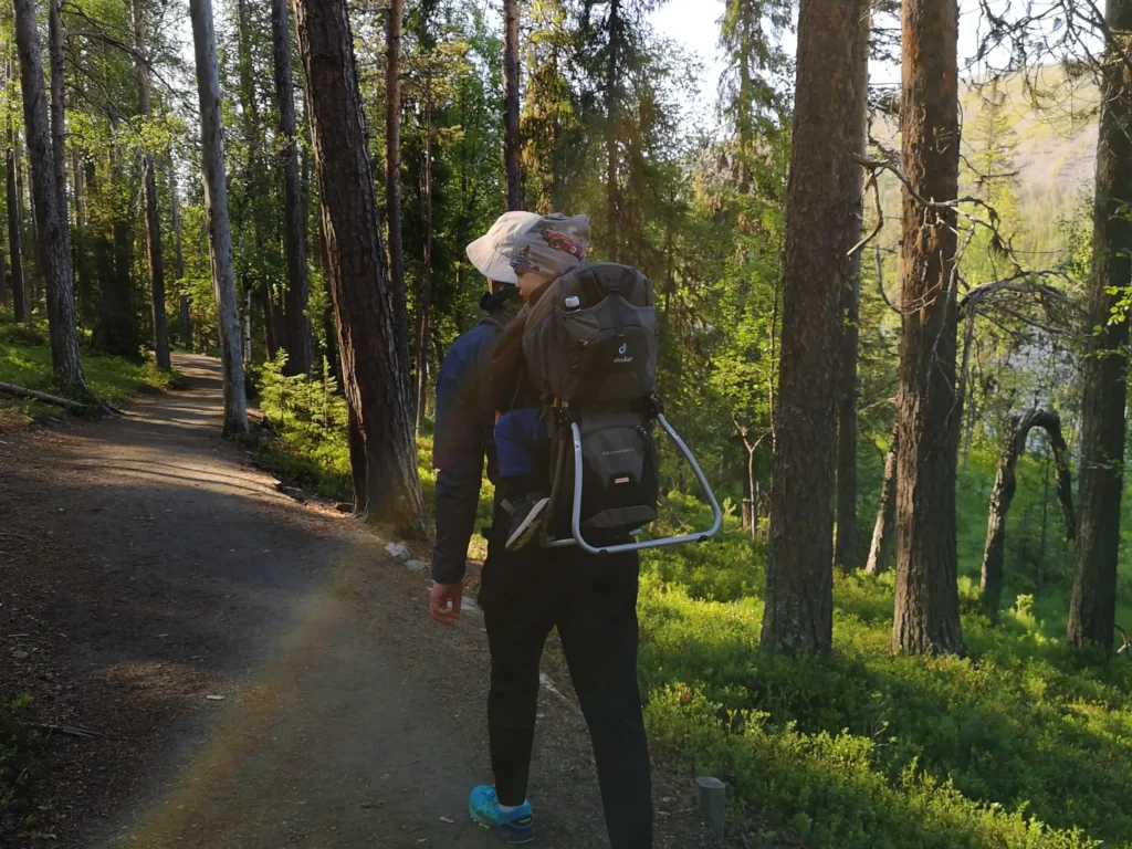 Man carrying a child in a nature path in Kesänkijärvi. A fell can be seen on the background. 